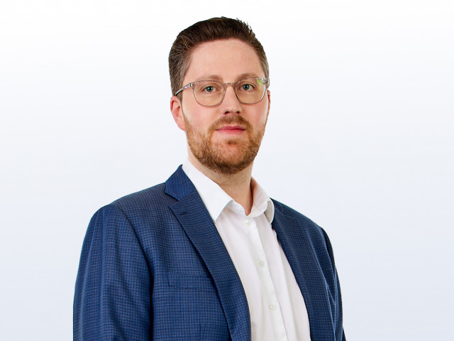 Der l&auml;chelnde TriFinance-Standortleiter in K&ouml;ln, Dirk Kl&uuml;mper,  blickt vor wei&szlig;em Hintergrund in die Kamera.